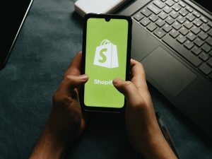 hands-holds-a-cell-phone-showing-the-shopify-logo