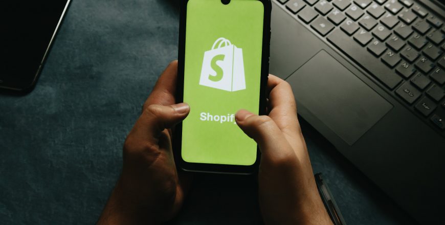 hands-holds-a-cell-phone-showing-the-shopify-logo